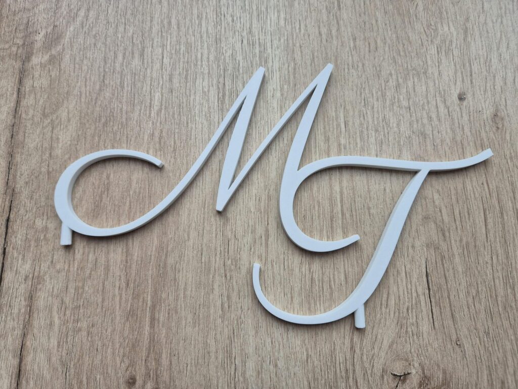 3D geprinte taarttopper met monogram in wit, op houten ondergrond